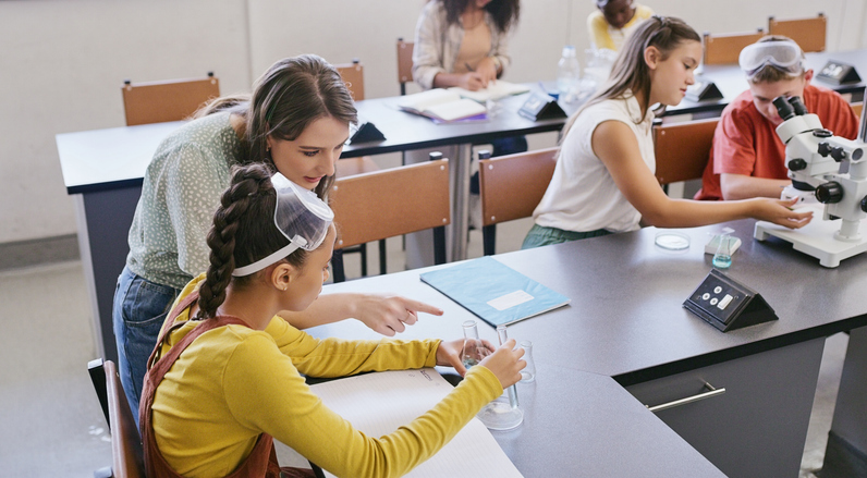 Science class teacher helping student in classroom