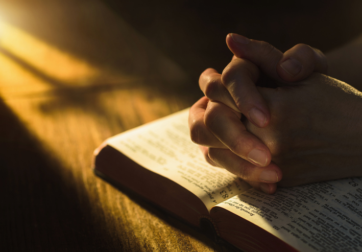 A woman in prayer with a Bible