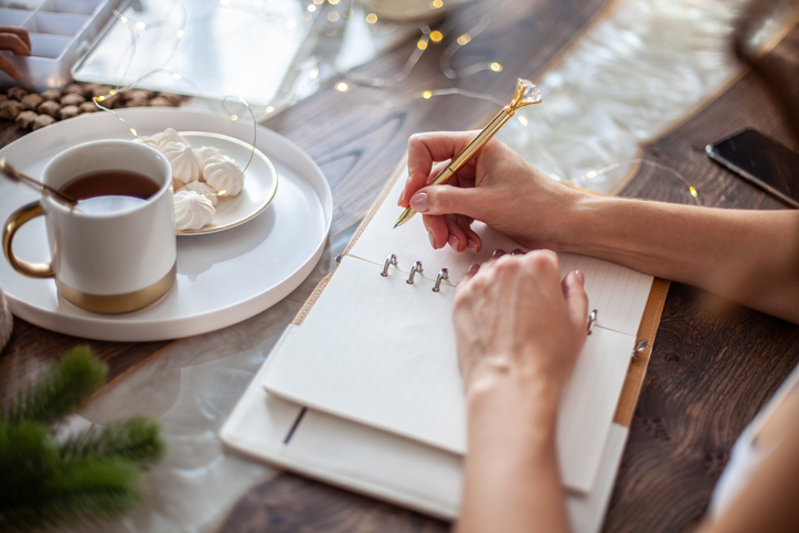 Young woman sitting with coffee and journaling her goals