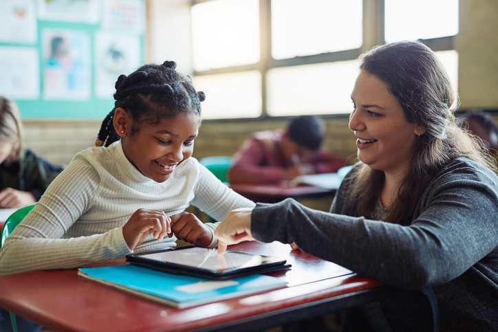 Teacher helping young student with tablet