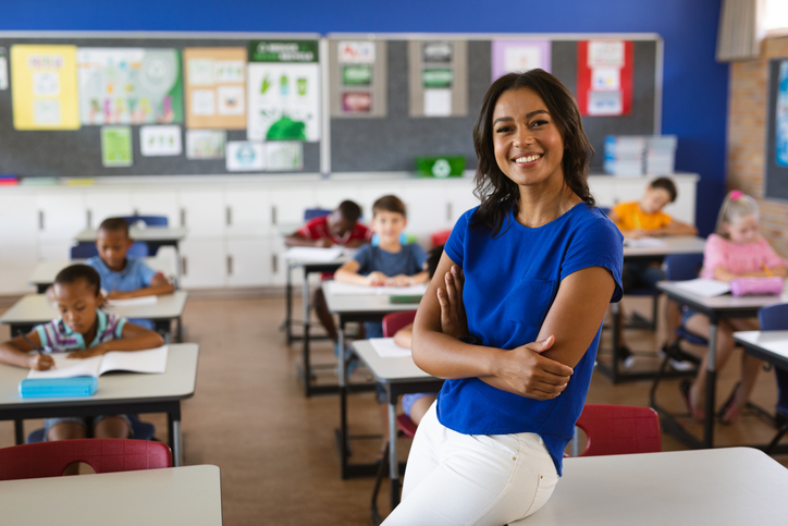 Female teacher smiling in front of classroom