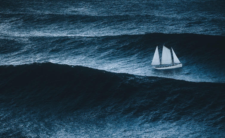 White sailboat sailing on large waves