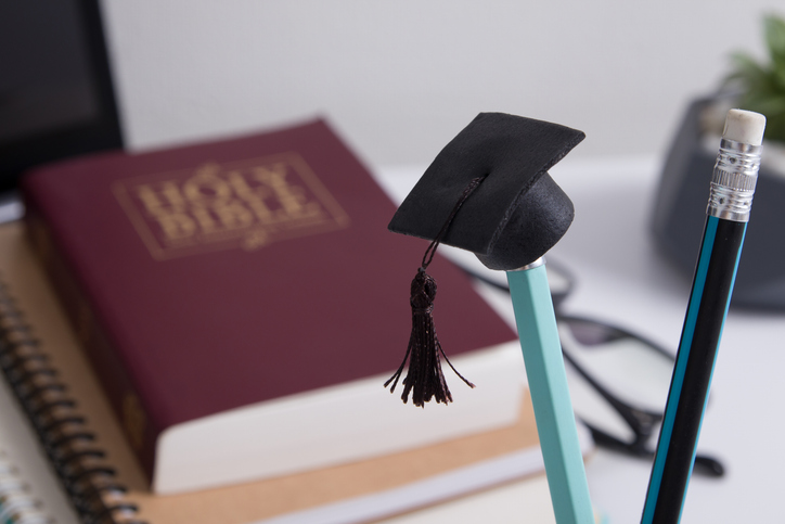 Pencil with graduation hat and q bible in the background.