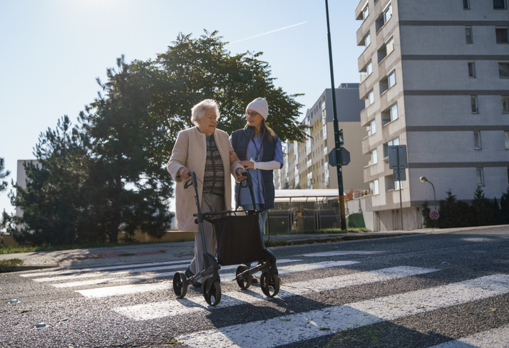girl helping older woman across the street