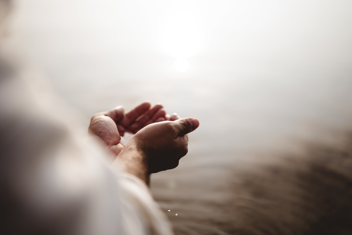Person cupping river water in hands.