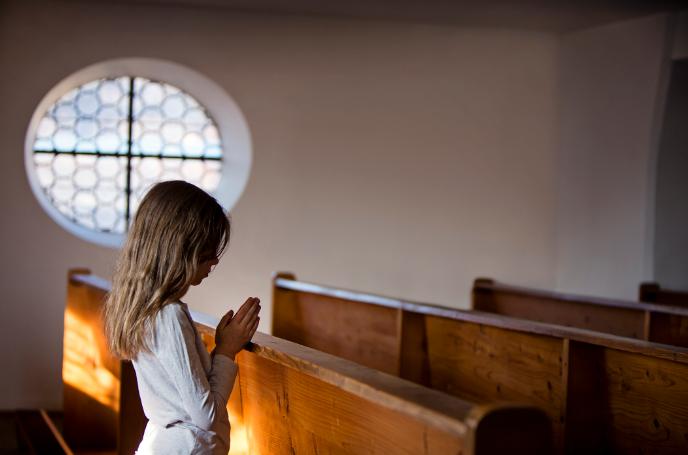 Little girl praying on pew