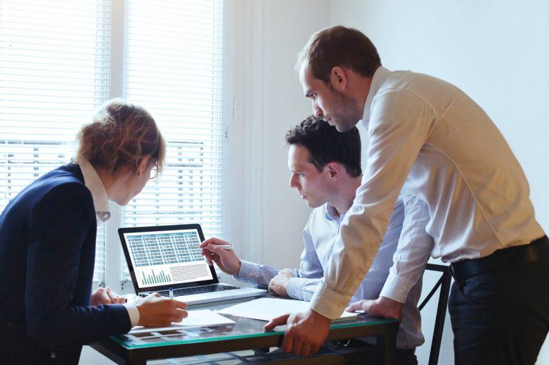 Business analyst shows two other professionals a report