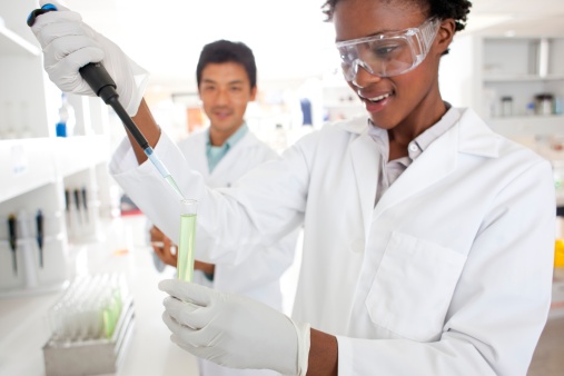 African-American female scientist putting a solution in test tube to use scientific method in a lab