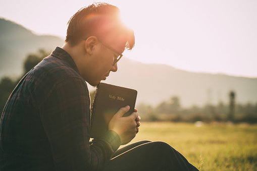 Man praying to Jesus Christ with Bible, surrendering to God