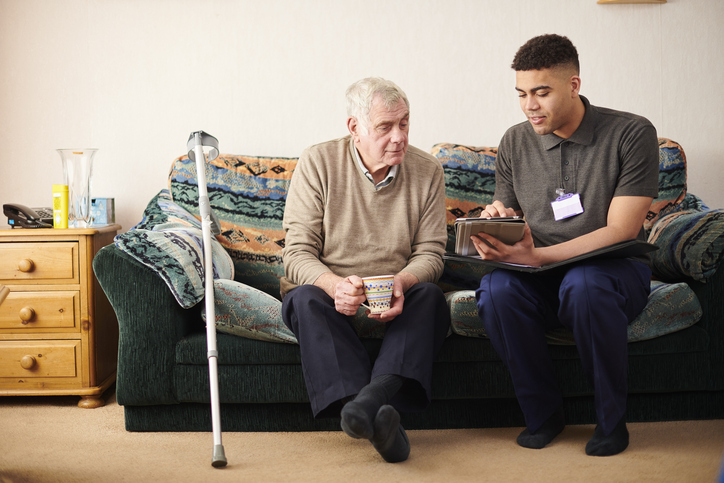 young male social worker meeting with elderly male client on couch