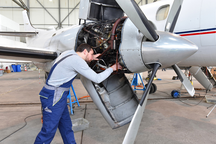 Aerospace mechanic repairing aircraft engine 