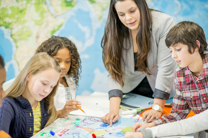 A history teacher helping her students find locations on a map