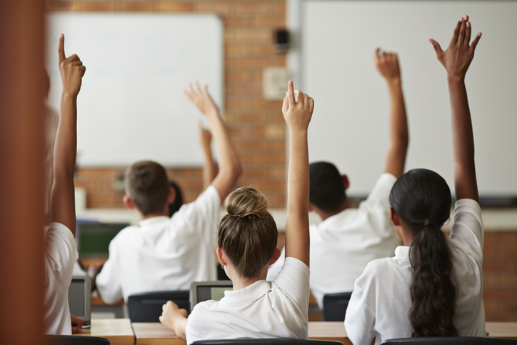 High school students raising their hands in class