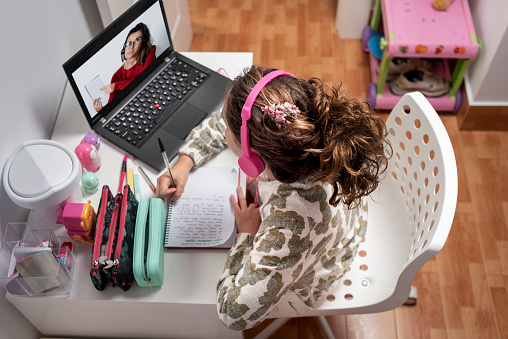 Young student completing lesson with teacher in an online classroom