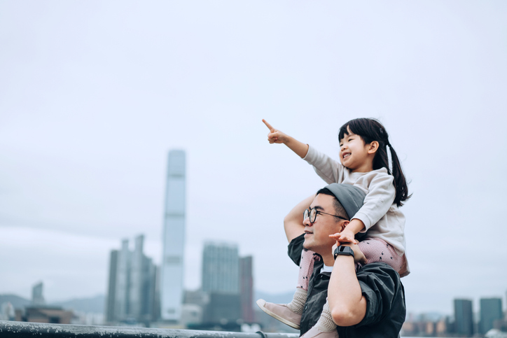 girl sitting on fathers shoulders pointing ahead of her