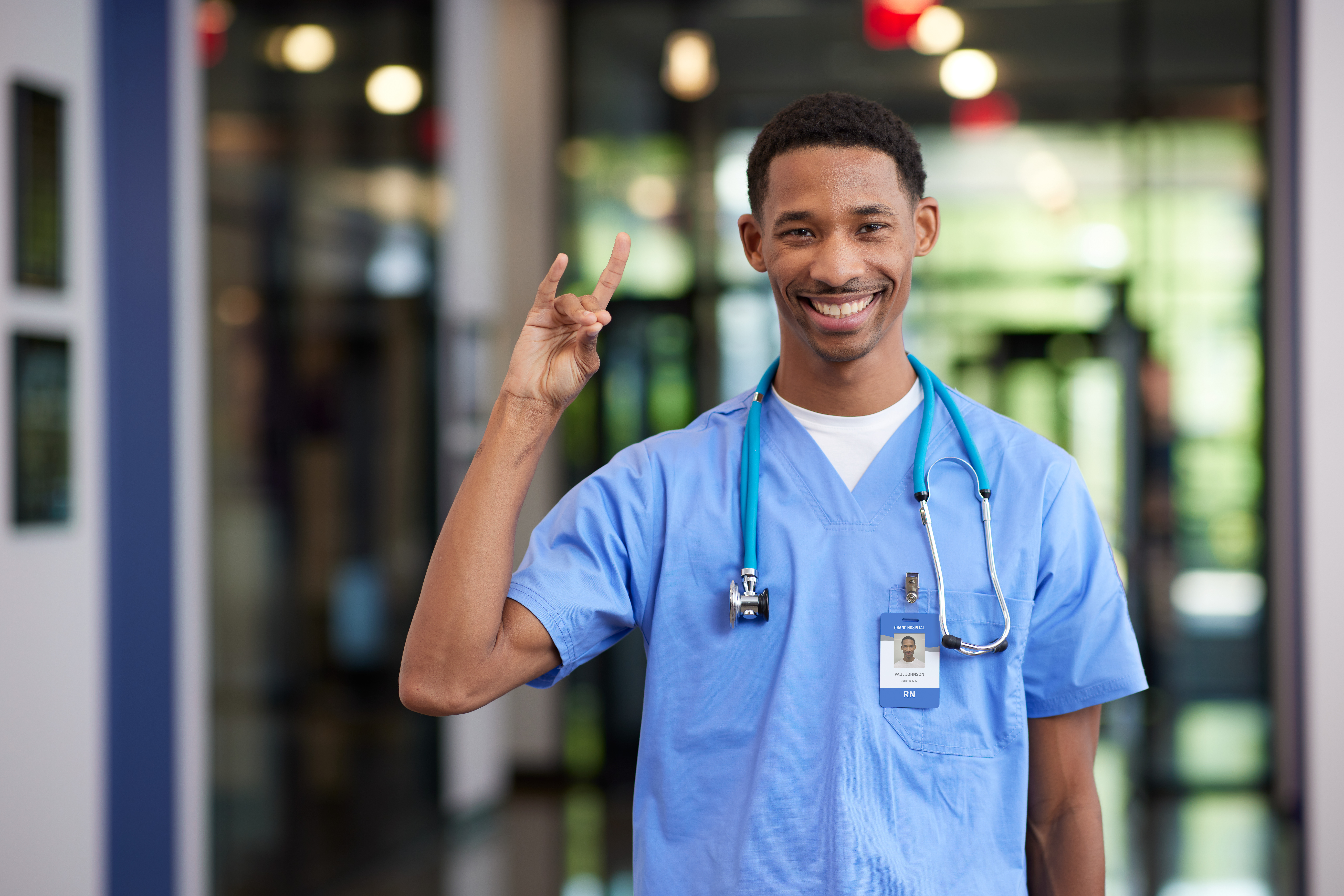 Male MSN degree student smiling with Lopes Up hand sign in hospital at GCU