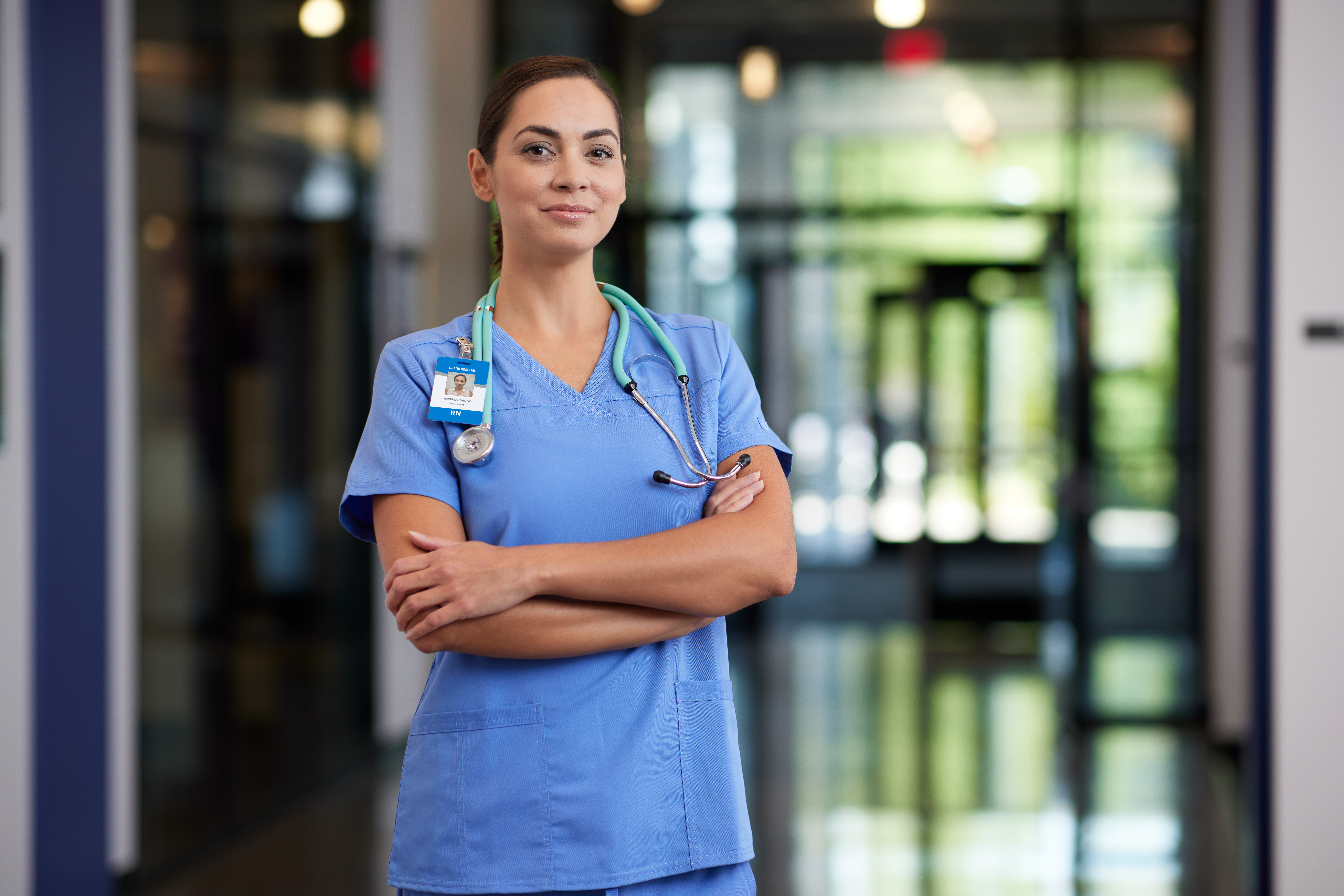 Portrait of female MSN degree graduate wearing blue scrubs in hospital hallway