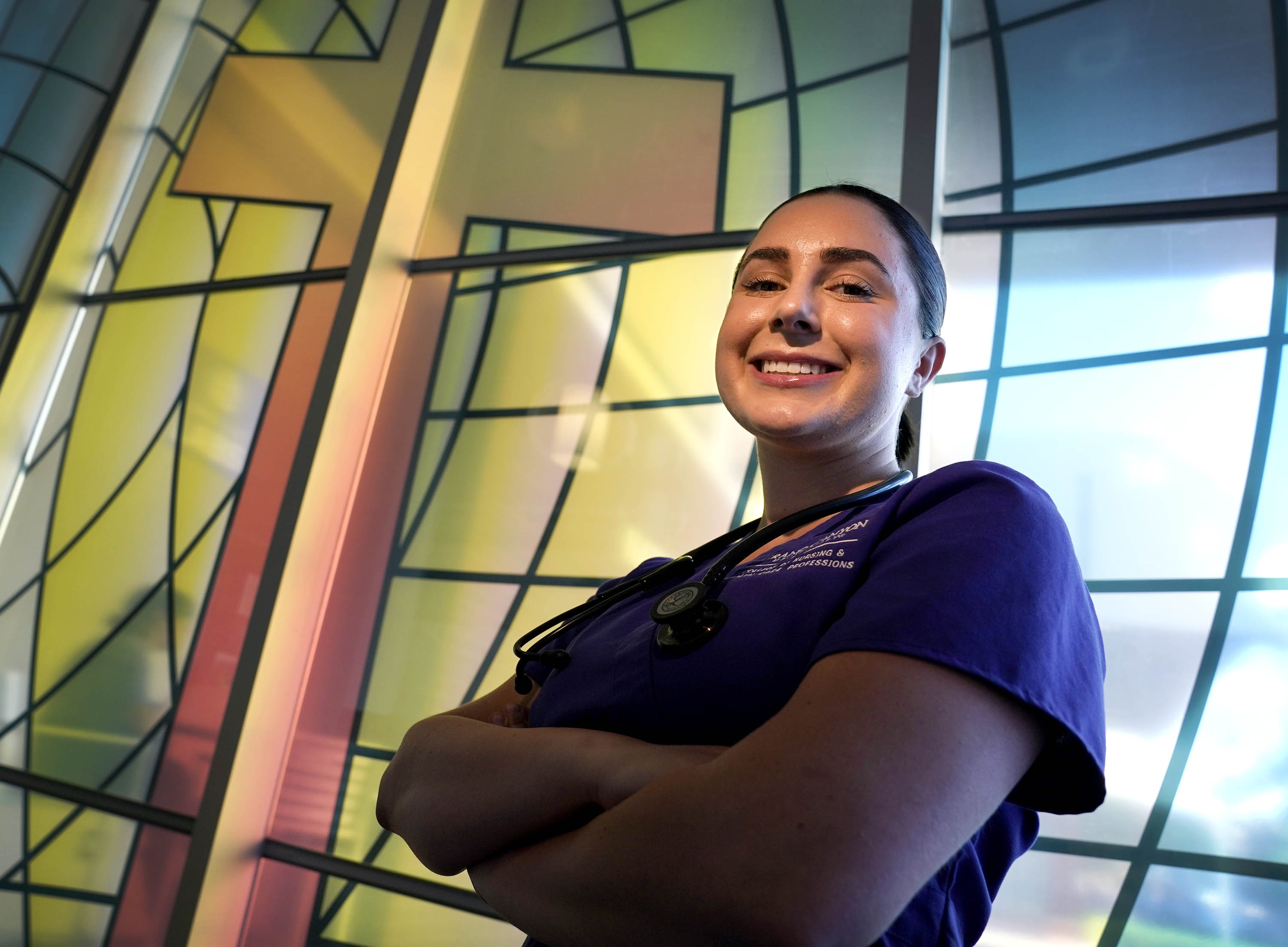 Female nursing degree student smiling in front of stained-glass window at GCU