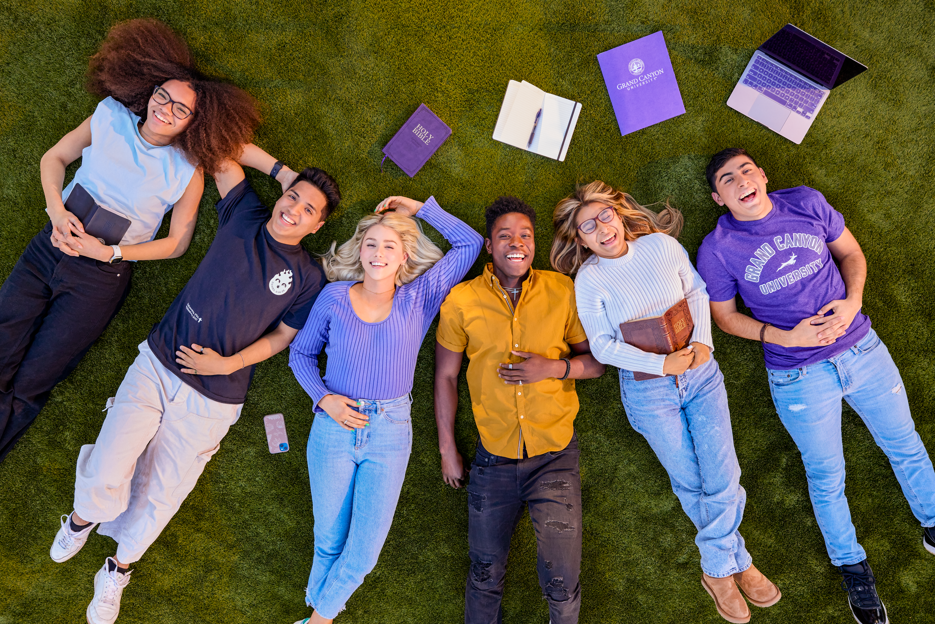 GCU students laying on the grass of a campus lawn